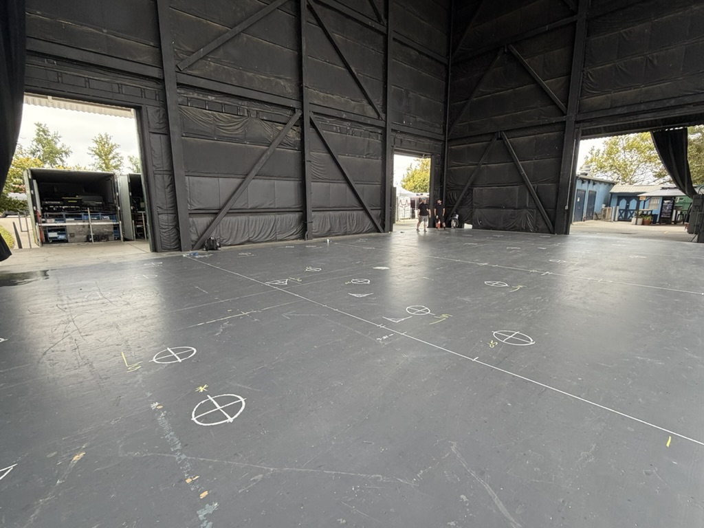 Wide shot of a staging floor covered in chalk point marks before rigging begins